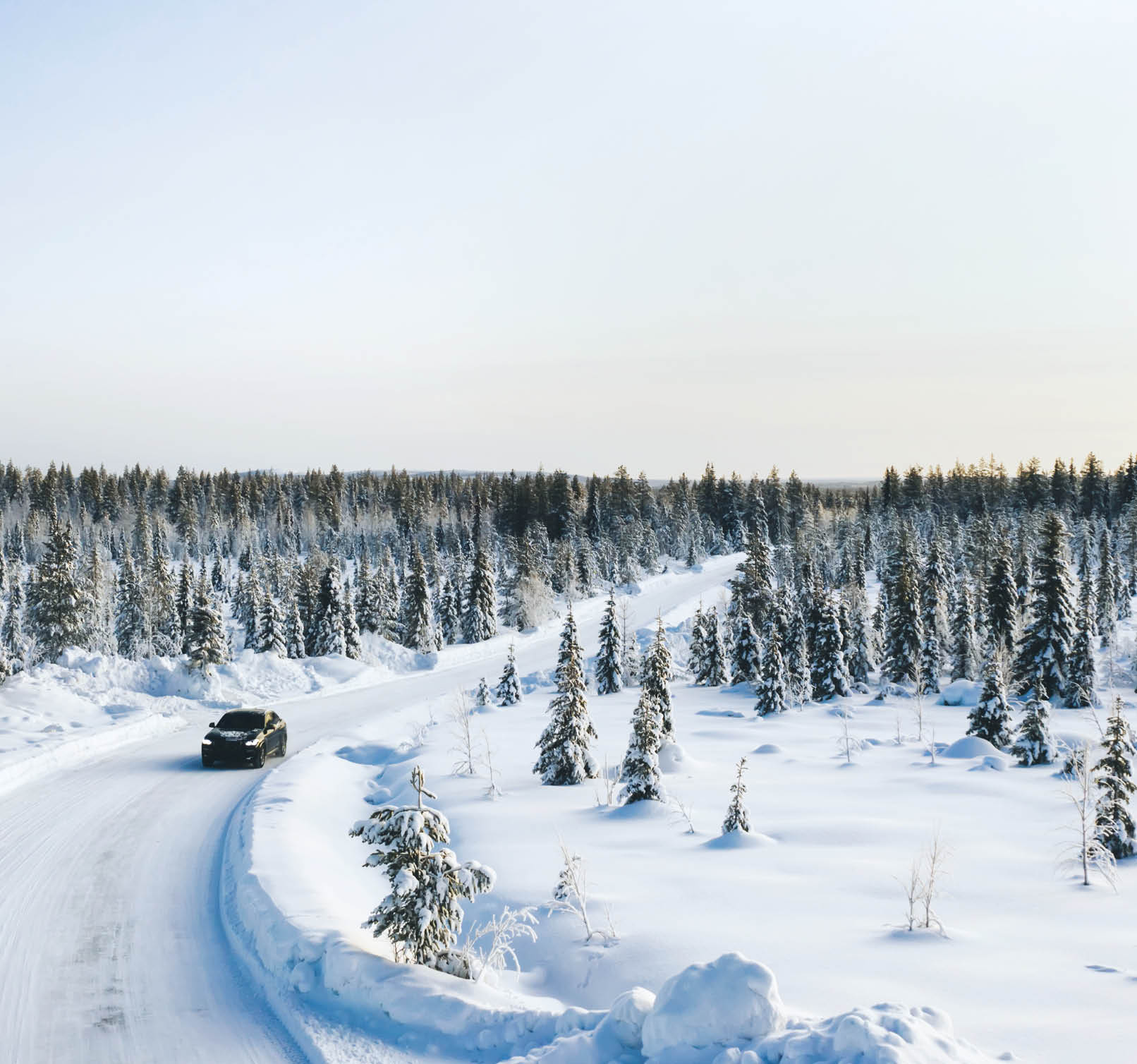 Bird €™s eye view of vehicle car moving on rural road having good insurance for winter weather, aerial view of suv automobile driving in scenery area surrounded by coniferous forest