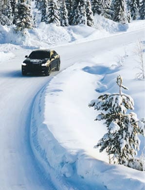 Bird €™s eye view of vehicle car moving on rural road having good insurance for winter weather, aerial view of suv automobile driving in scenery area surrounded by coniferous forest