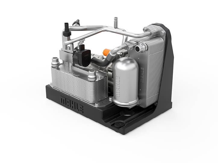 Ein komplexes technisches Bauteil aus Metall mit Rohren, Ventilen und einem schwarzen Sockel, das wie eine kompakte Maschine oder ein Motor aussieht. Beschreibung von KI generiert