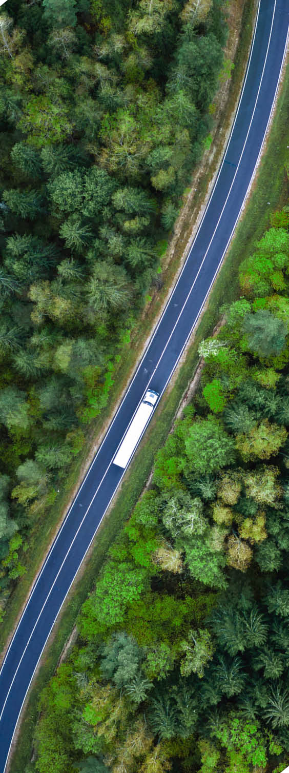 Arial view of heavy truck on a narrow twisting road. Autumn colorful trees by the sides of the road.